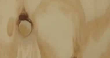 Abstract beige-toned image with soft textures and a dark circular mark on the left, suggesting an impression of depth or eyes in a painting.